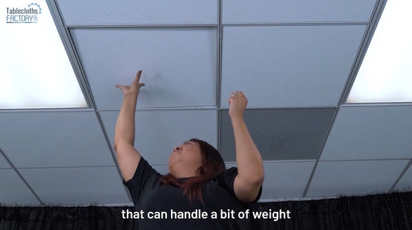Person reaching for a secure ceiling spot to support the weight of a disco ball.