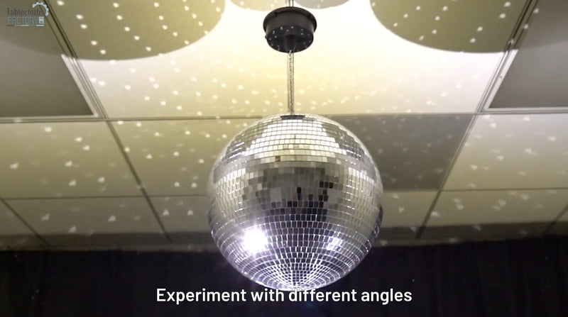 Disco ball reflecting light on the ceiling, creating sparkling patterns with angled beams.