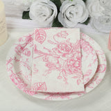 Pink floral dinnerware set with plates and napkins on a textured tablecloth.