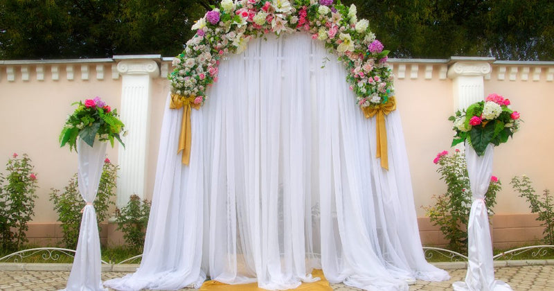 Wedding arch draped in white fabric with floral garland