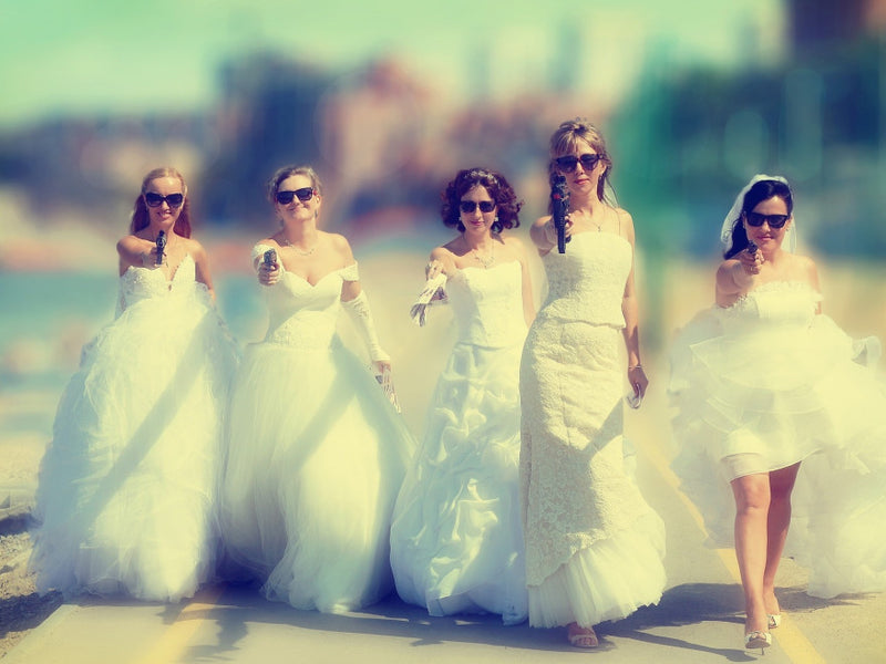 Five women in white dresses holding pistols