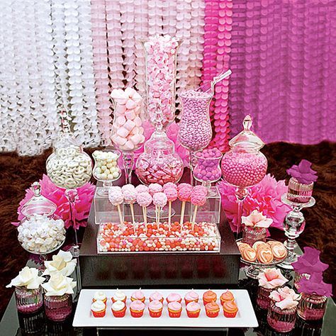 Pink candy buffet display with jars, lollipops, and cupcakes