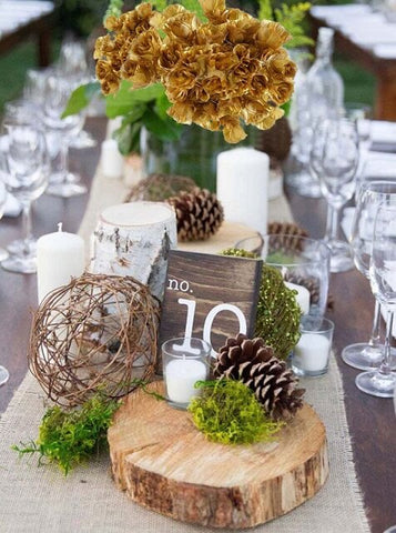 Rustic table centerpiece with wood slices, moss, and candles