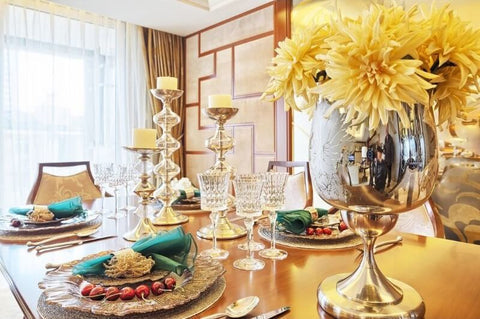 Gold geometric lanterns with candles and greenery on a table