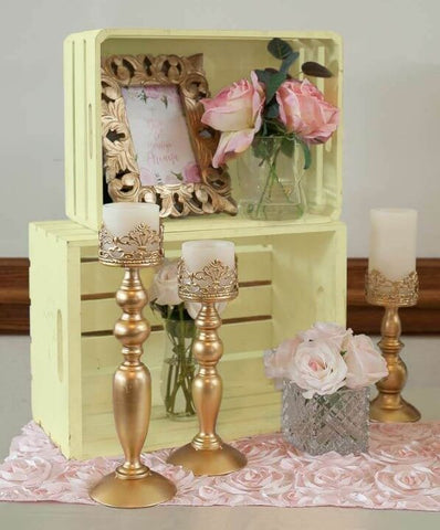 Gold candle holders and flowers on a pink table runner
