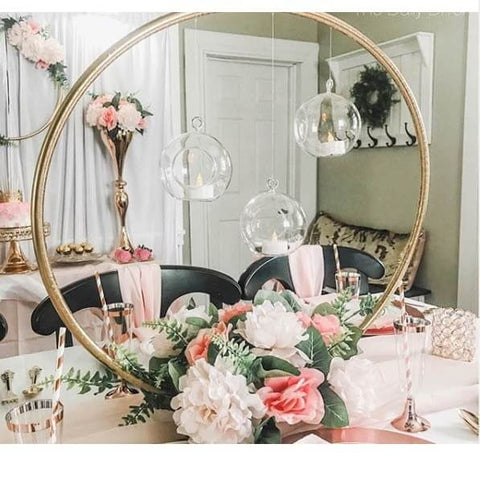 Gold hoop centerpiece with hanging glass globes and flowers