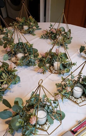 Geometric gold lantern centerpieces with greenery and candles