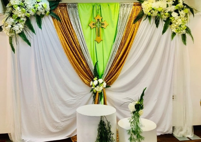Decorated backdrop with white, green, and gold drapes