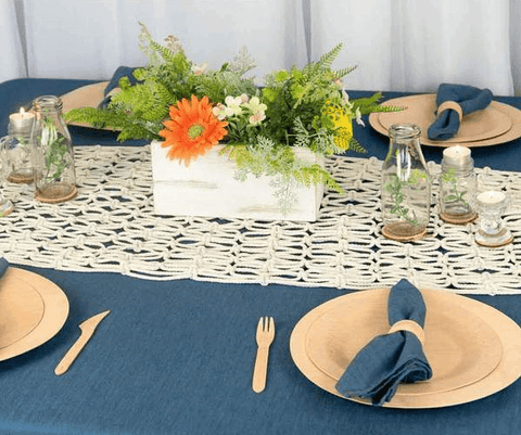 Blue table with white macramé runner and gold plates