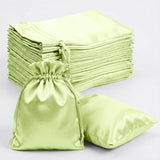 Green satin bags and pillowcases stacked neatly on a plain background.