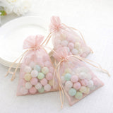 Pastel candy-filled organza bags on a light table setting.