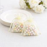 Pastel candy in sheer organza gift bags on a white table setting