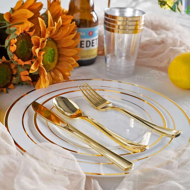 Gold disposable fork, spoon, and knife on a clear plate