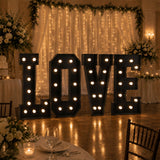 Illuminated LOVE marquee letters at a romantic wedding reception backdrop