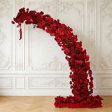 Red floral arrangement in elegant design against a classic white wall.