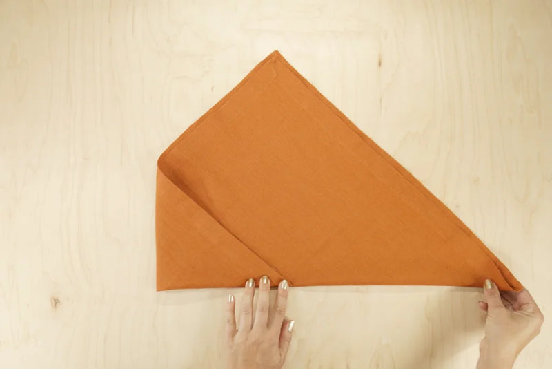 Orange napkin being folded into an envelope shape