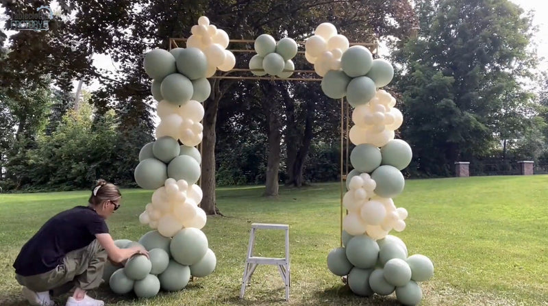 Partially completed balloon arch with dusty sage green and pastel beige balloons being assembled.