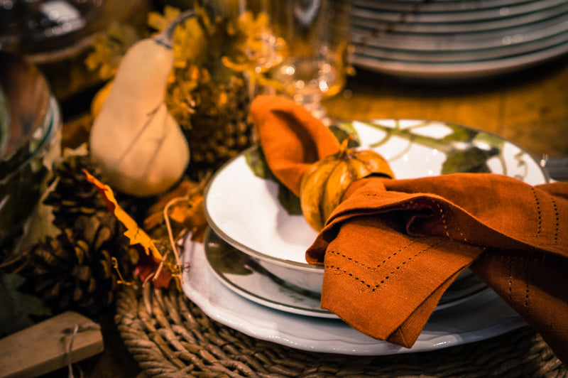 Orange napkin on stacked plates with small gourd