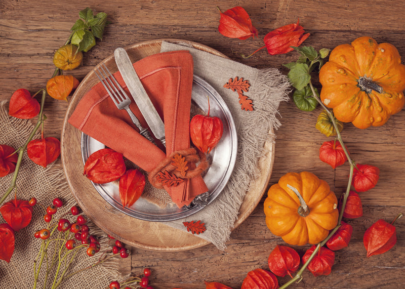 Autumn place setting with orange napkin and pumpkins
