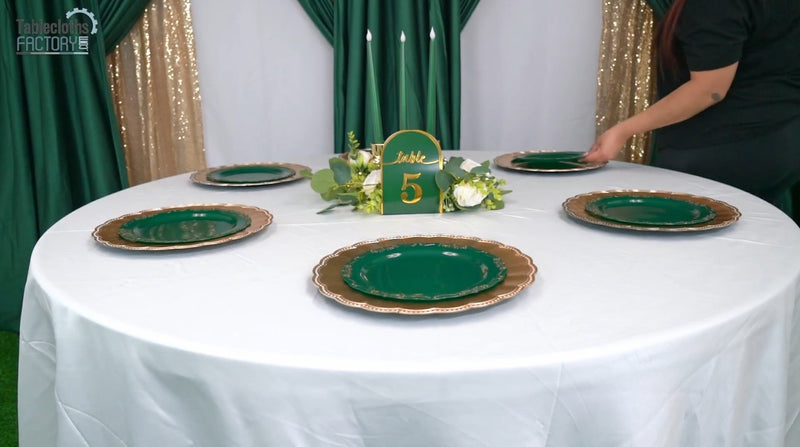 Placing plates during green and gold table decor setup with floral accents.