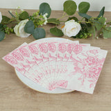 Decorative pink floral napkins arranged on a plate with greenery backdrop.