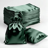 Green satin drawstring bags and pillows stacked on a plain background.