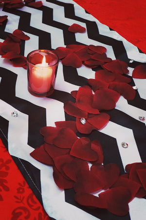 Red rose petals on a black-and-white chevron table runner