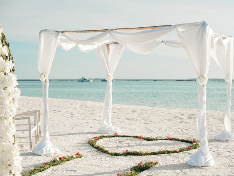 Beach wedding ceremony arch with white draping