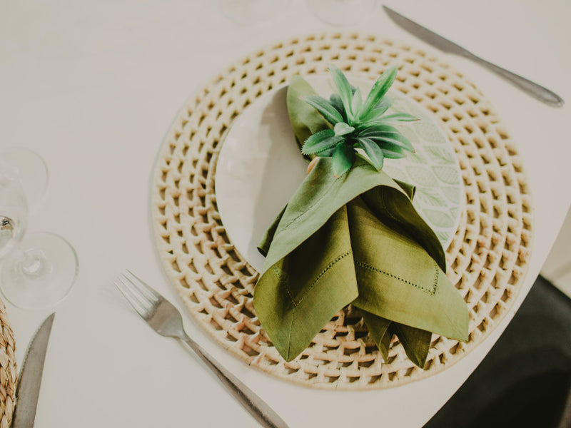 Green napkin folded on a woven placemat