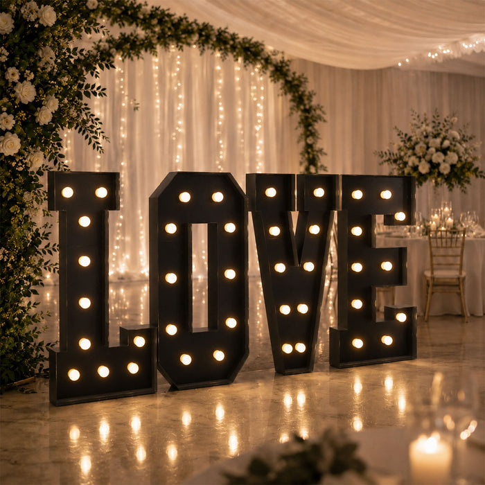 Illuminated “LOVE” marquee letters at elegant wedding reception backdrop