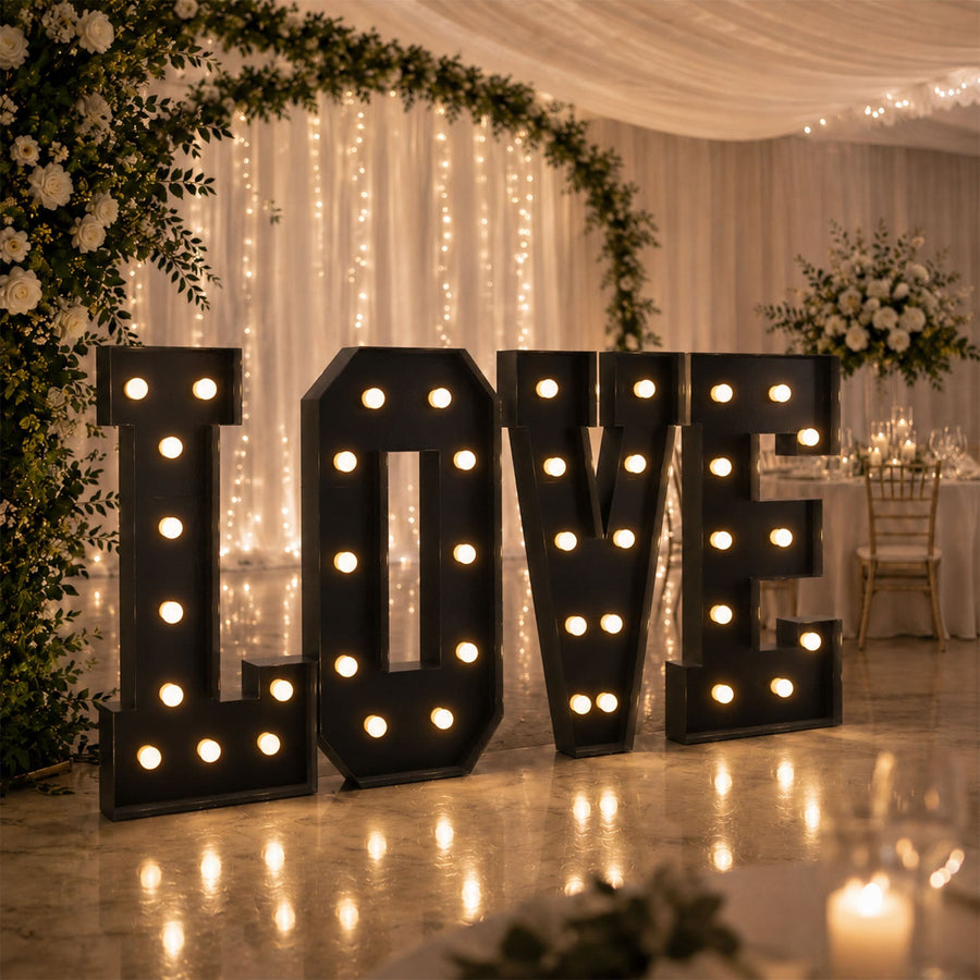 Illuminated “LOVE” marquee letters at elegant wedding reception backdrop