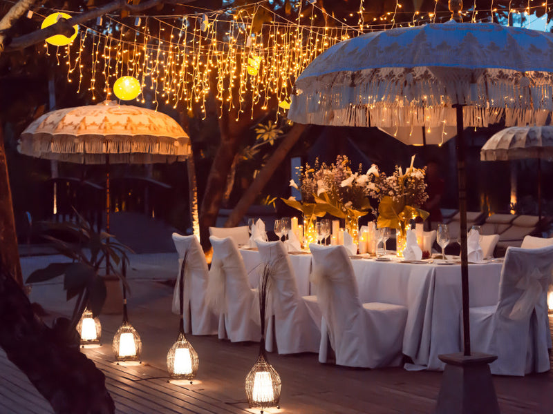 Outdoor dinner table with string lights and fringed parasols