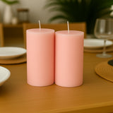 Pink pillar candles on a wooden table setting.