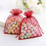Red organza bags filled with colorful candy balls on a plain background.