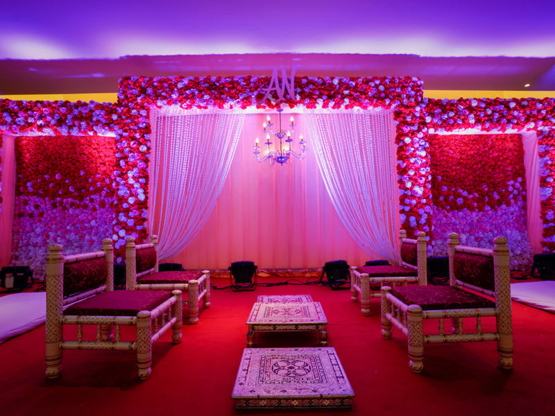 Wedding stage with floral backdrop, draped curtains, and seating