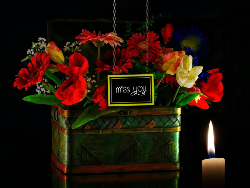 Memorial floral arrangement in a woven basket with a candle