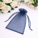 Navy organza drawstring bag with puffed top against a floral backdrop.