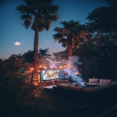 Outdoor movie screen lit under palm trees at night