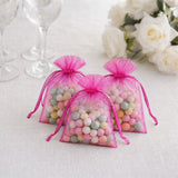 Pink organza gift bags filled with pastel candy balls on a white table