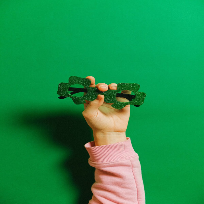 Hand holding green shamrock sunglasses