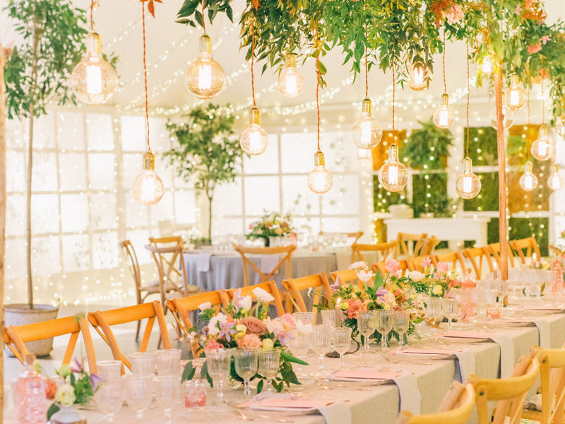 Reception table with hanging lights and pastel floral centerpieces