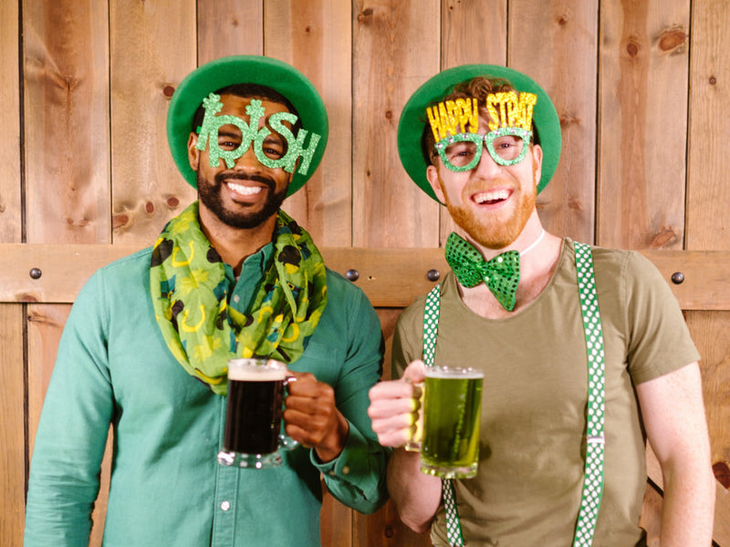Two men holding drinks in St. Patrick's Day outfits