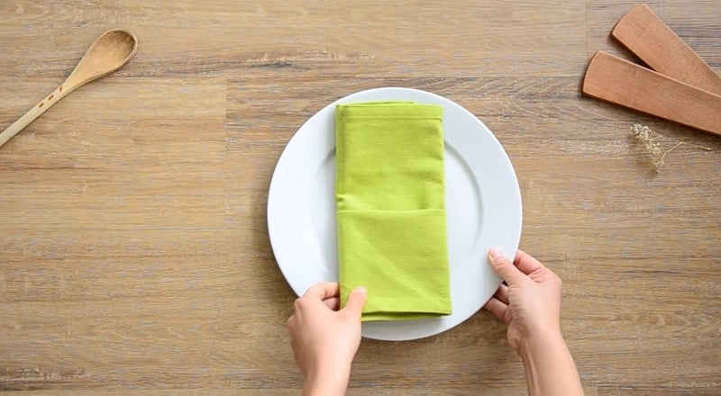 Green napkin folded vertically on a white plate