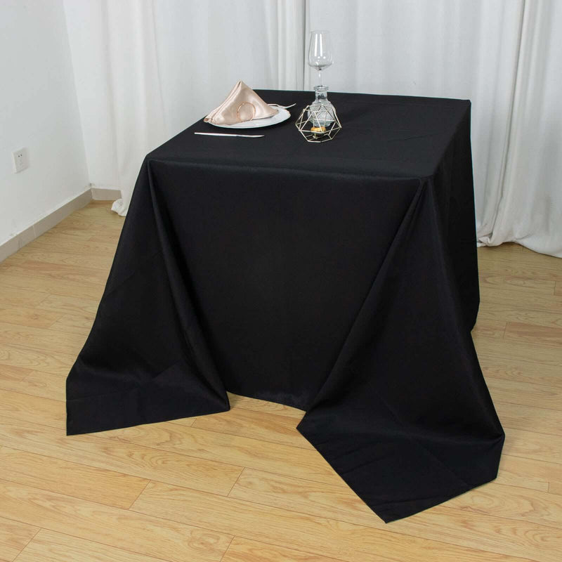Black square tablecloth on a table with place setting