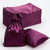 Purple satin drawstring bags stacked and one bag displayed in front.