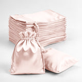 Stack of pink satin drawstring bags on a white background.