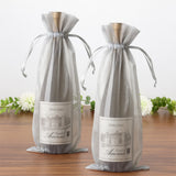 Two elegant wine bottles in sheer gray gift bags on a wooden surface.