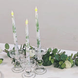 White and sage green flameless LED taper candles in glass holders.