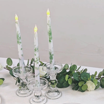 White and sage green flameless LED taper candles in glass holders.
