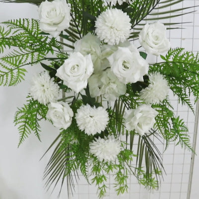 Ivory rose and chrysanthemum wedding arch flowers with greenery and palm leaves.